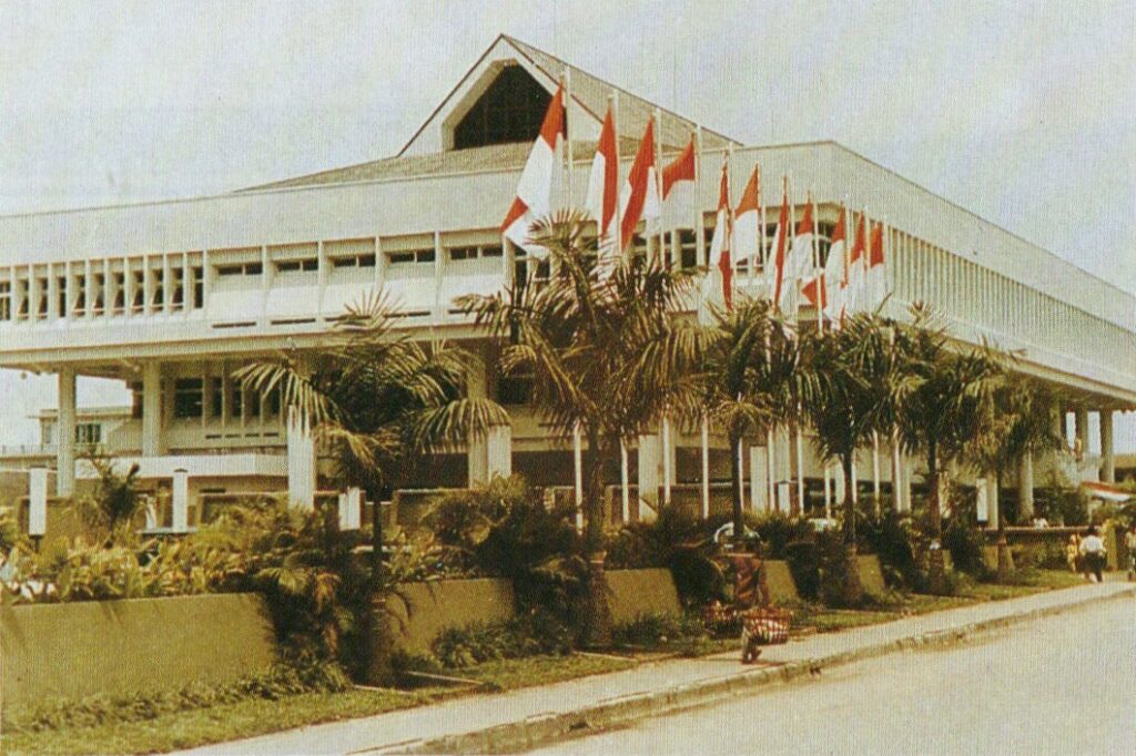 Gedung Keuangan Negara Balikpapan, April 1982, gedung berwarna putih dengan atap gaya lamin, dengan 11 bendera Indonesia di depan. Balikpapan tempo dulu 1980an.